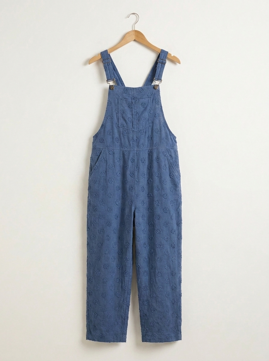Blue linen dungarees on a wooden hanger