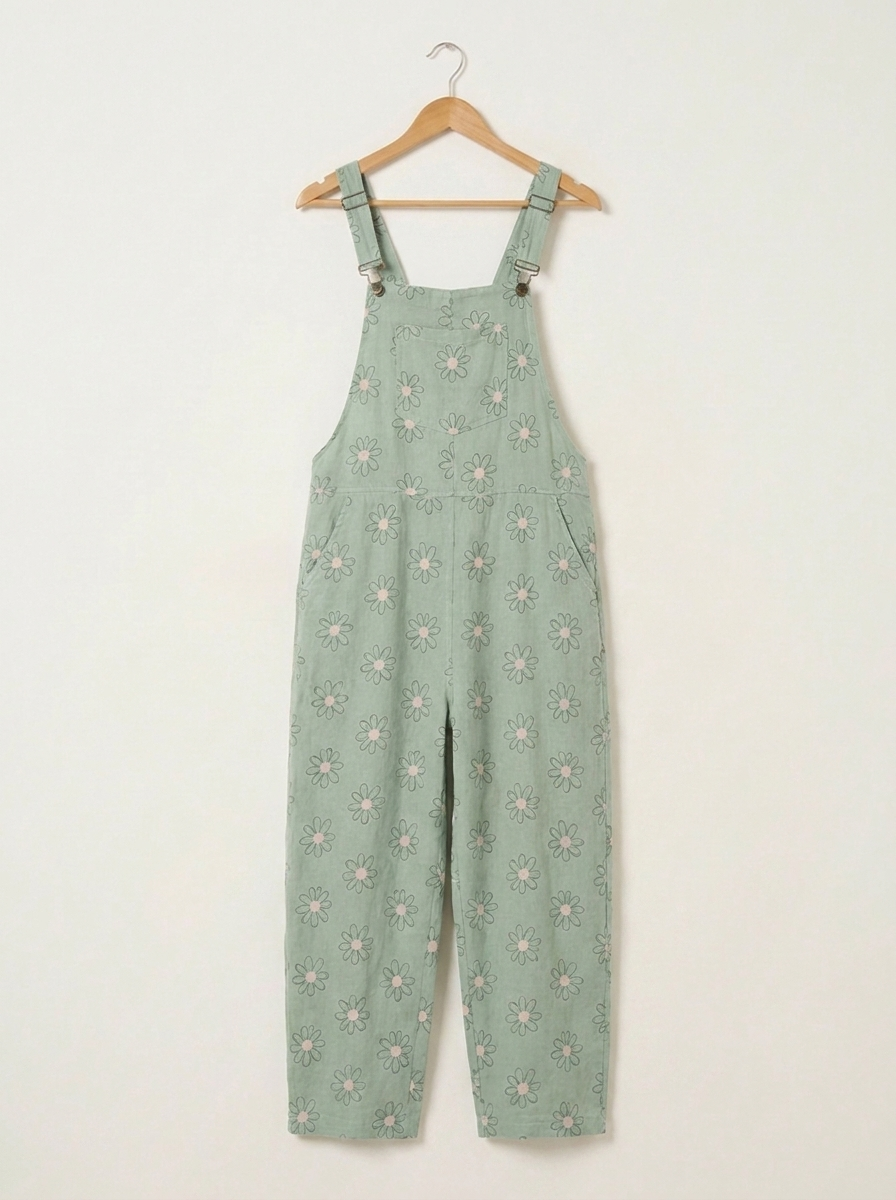 Mint daisy print linen dungarees on a wooden hanger