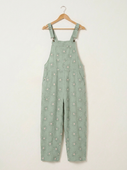 Mint daisy print linen dungarees on a wooden hanger