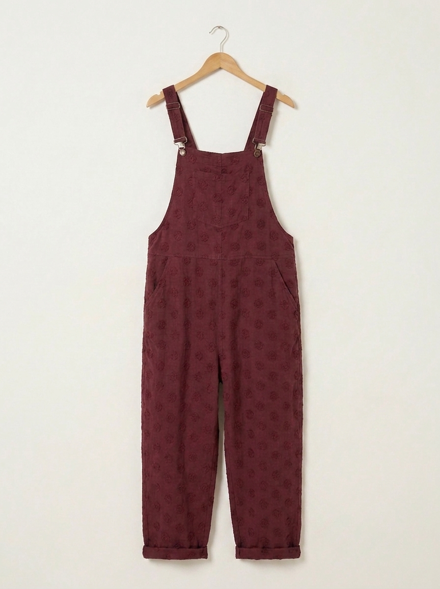 Burgundy linen dungarees on a wooden hanger