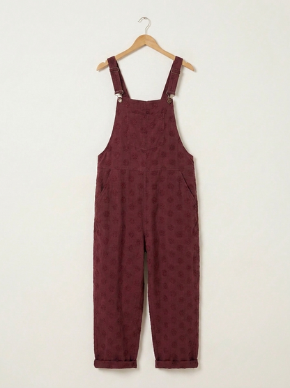 Burgundy linen dungarees on a wooden hanger